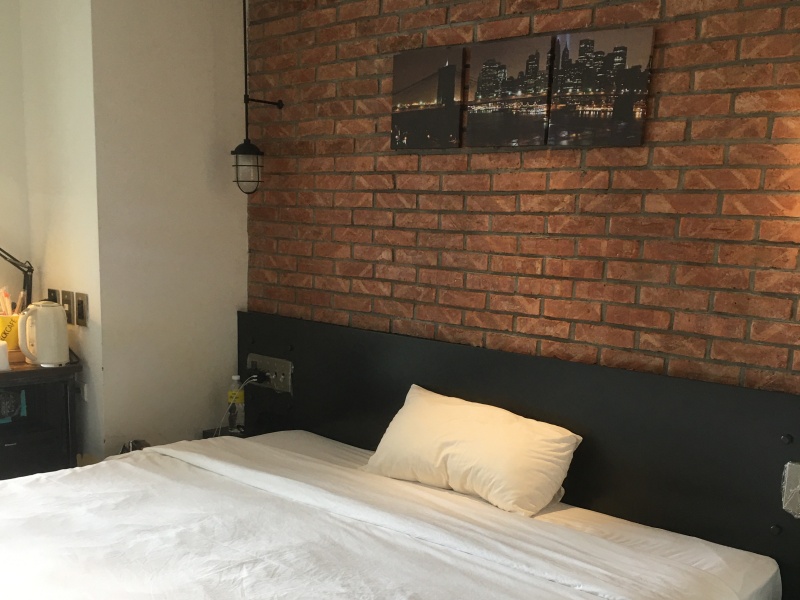 quarantine hotel bed against brick wall