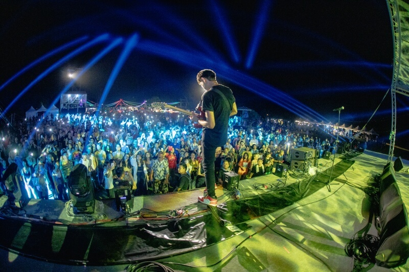 man playing guitar on stage at pasiwali