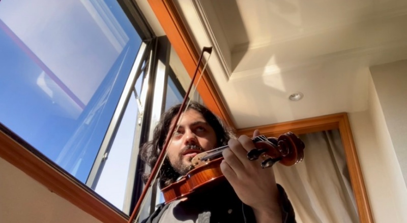 man next to window holding violin